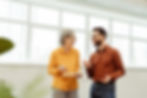 Two colleagues laughing and discussing in a brightly lit office, highlighting a positive workplace environment